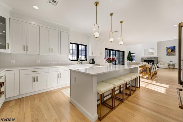 kitchen with visible vents, light wood-style flooring, light countertops, white cabinetry, and a center island