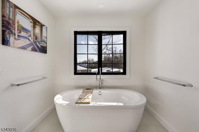 full bath with a soaking tub and baseboards