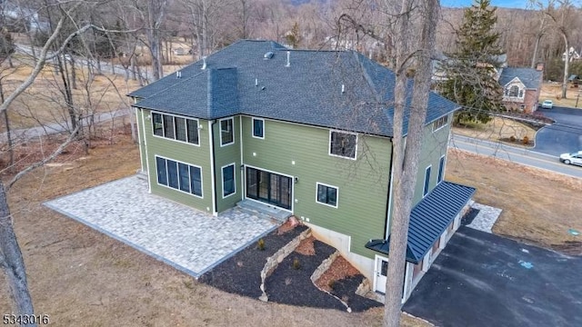 back of house featuring roof with shingles