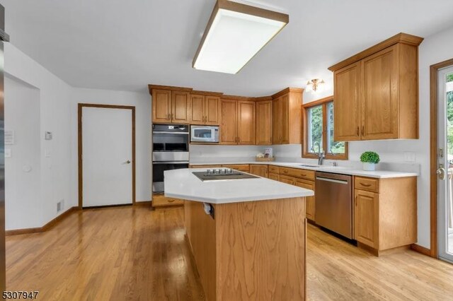 kitchen with a sink, light countertops, light wood-type flooring, and stainless steel appliances