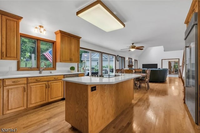 kitchen featuring a sink, open floor plan, a center island, light wood-style floors, and light countertops