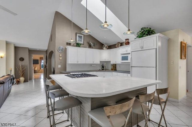 kitchen with white appliances, arched walkways, light tile patterned flooring, and white cabinets