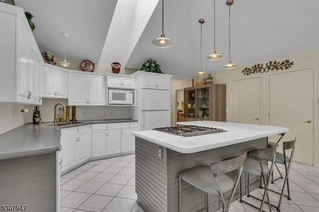 kitchen with a breakfast bar, a sink, white appliances, white cabinets, and light tile patterned floors