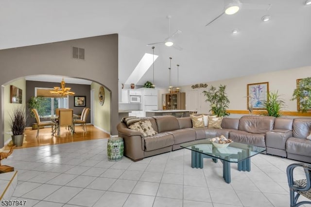 living room featuring visible vents, high vaulted ceiling, ceiling fan with notable chandelier, arched walkways, and light tile patterned floors