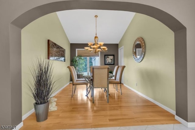 dining space with vaulted ceiling, wood finished floors, baseboards, and a chandelier