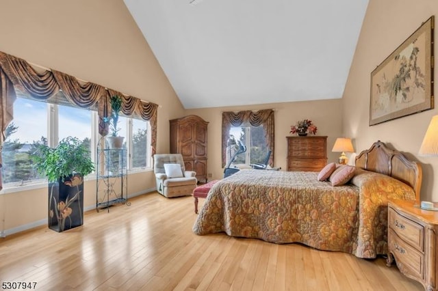 bedroom with baseboards, light wood-style floors, and high vaulted ceiling