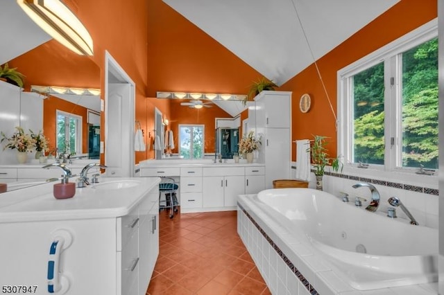 bathroom with tile patterned floors, a tub with jets, two vanities, and a sink