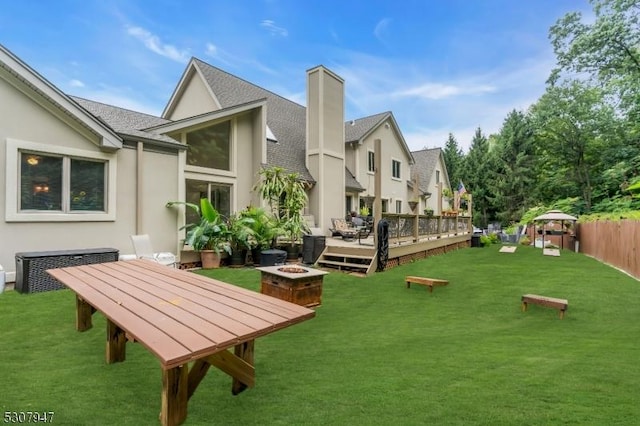 view of community with a yard, a fire pit, fence, and a wooden deck