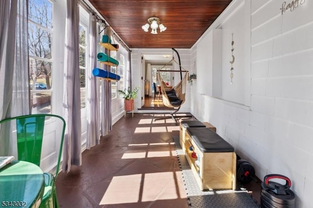 corridor with a chandelier, wooden ceiling, and concrete block wall