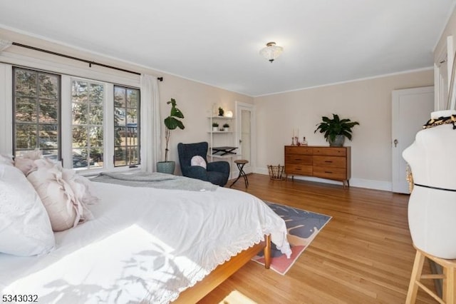 bedroom with baseboards, light wood-style floors, and ornamental molding