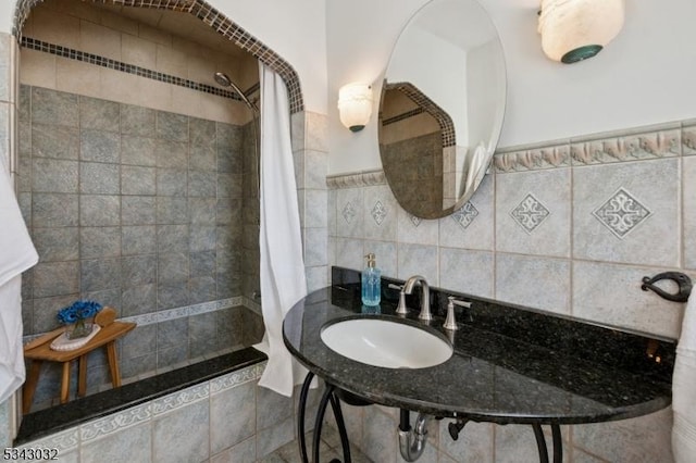 bathroom with a sink, tiled shower, and tile walls