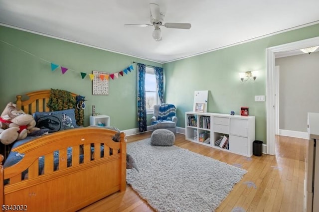 bedroom featuring crown molding, wood finished floors, baseboards, and ceiling fan