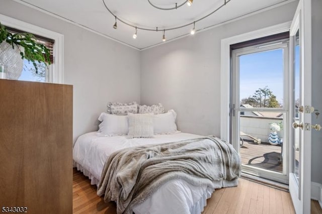 bedroom with track lighting, access to outside, and light wood-type flooring