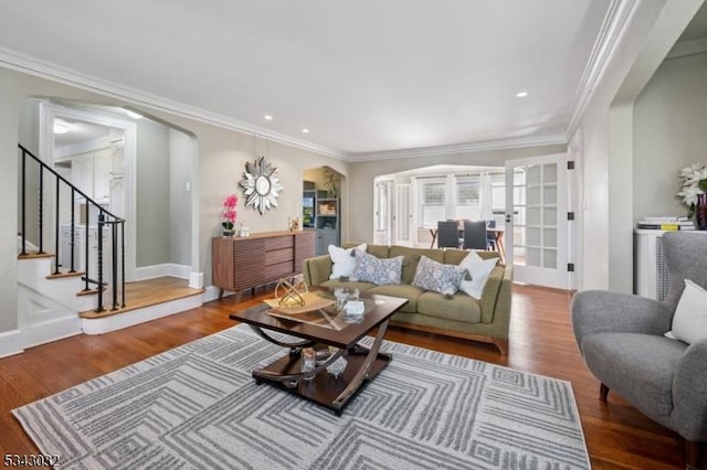 living area with ornamental molding, wood finished floors, french doors, arched walkways, and stairs