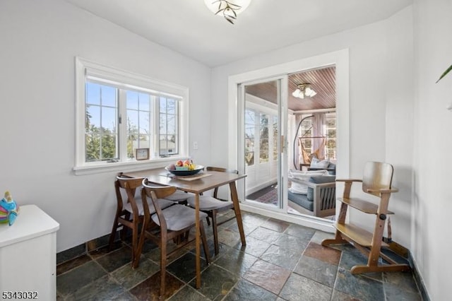 dining room with stone tile floors and baseboards