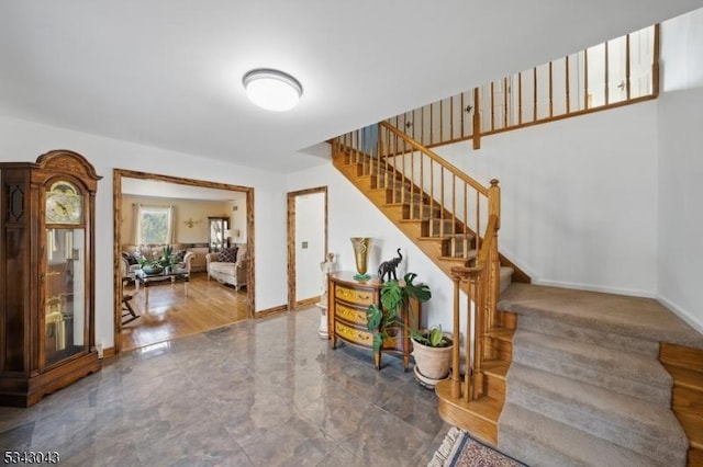 foyer entrance featuring stairway and baseboards