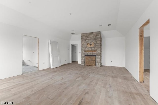 unfurnished living room featuring a fireplace, light wood-style floors, and lofted ceiling