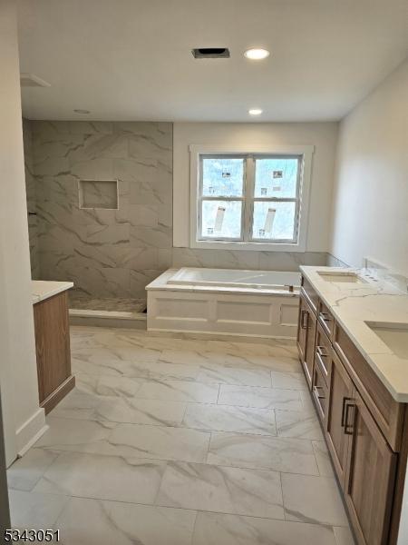 bathroom with marble finish floor, a walk in shower, a sink, double vanity, and a bath