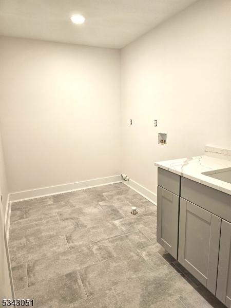 washroom featuring baseboards, recessed lighting, cabinet space, a sink, and washer hookup