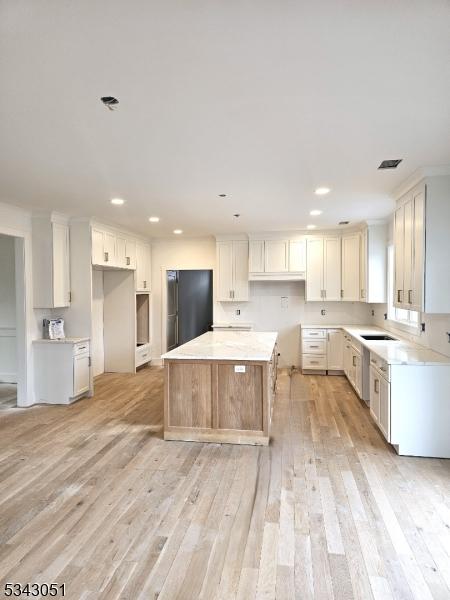 kitchen with visible vents, light wood finished floors, recessed lighting, freestanding refrigerator, and a center island