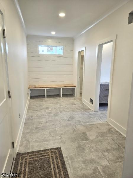 corridor featuring recessed lighting, baseboards, ornamental molding, and wood walls