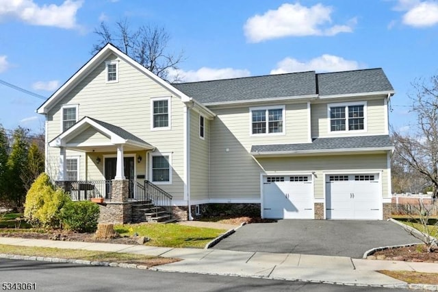 traditional-style house featuring a garage, roof with shingles, and aphalt driveway