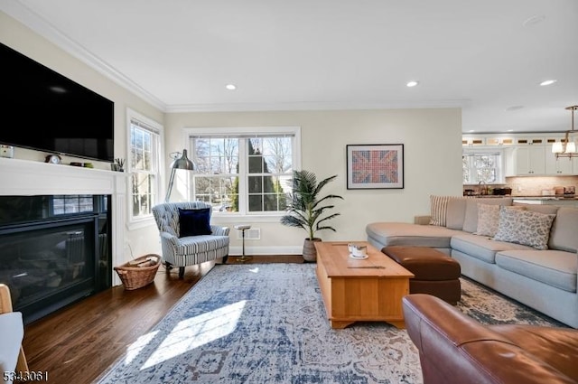 living area featuring recessed lighting, ornamental molding, a healthy amount of sunlight, and wood finished floors