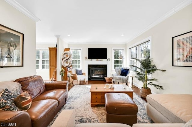 living area with a glass covered fireplace, recessed lighting, and crown molding