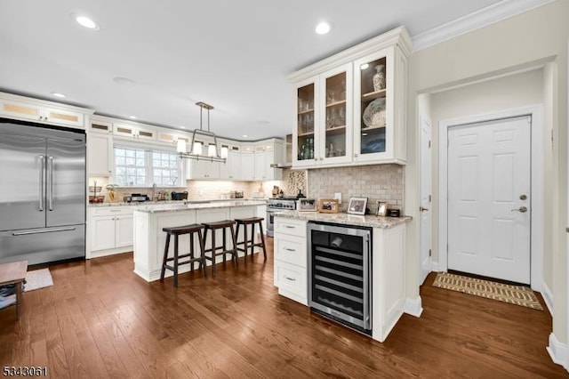 kitchen featuring backsplash, wine cooler, a breakfast bar, white cabinets, and high end appliances