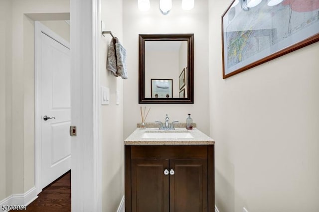 bathroom with baseboards, wood finished floors, and vanity