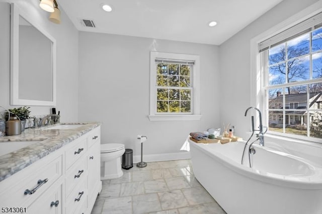 full bath with visible vents, baseboards, double vanity, a soaking tub, and a sink