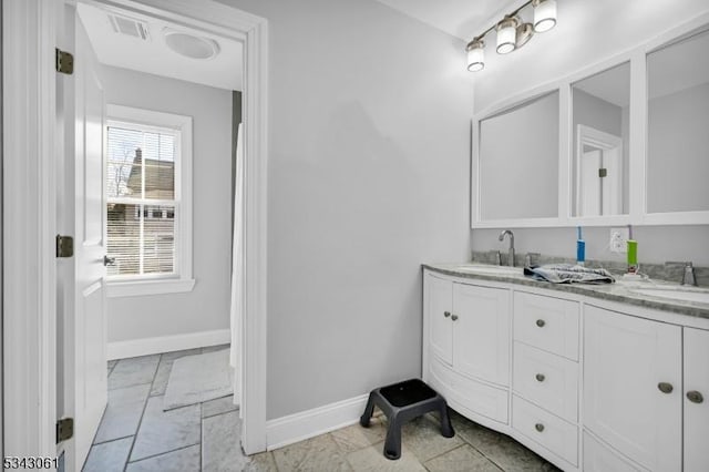 full bath featuring double vanity, baseboards, visible vents, and a sink