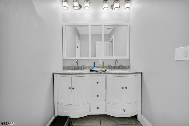 full bathroom featuring double vanity, baseboards, and a sink