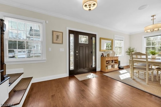 foyer entrance with ornamental molding, baseboards, and wood finished floors