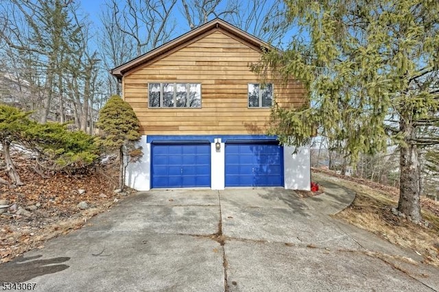 view of side of home with an attached garage, driveway, and stucco siding