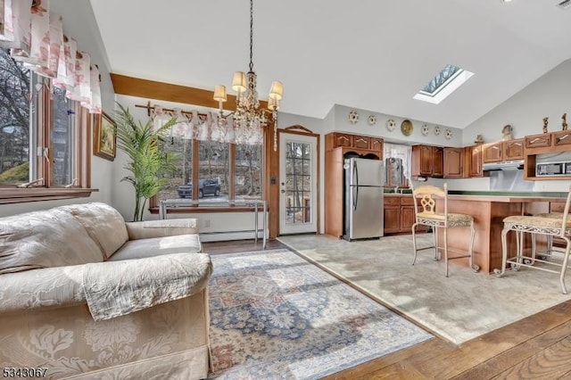 kitchen with a breakfast bar, under cabinet range hood, open floor plan, stainless steel appliances, and a baseboard radiator