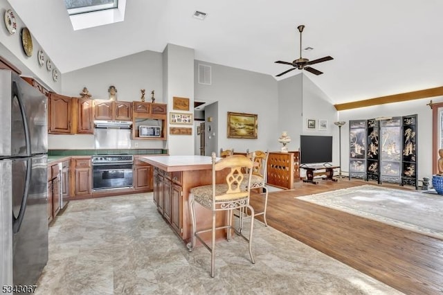 kitchen featuring visible vents, a kitchen island, appliances with stainless steel finishes, a skylight, and light countertops