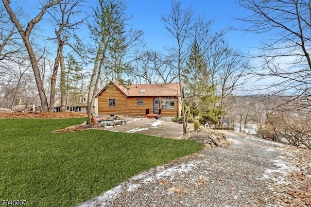 rear view of house featuring entry steps, driveway, and a yard