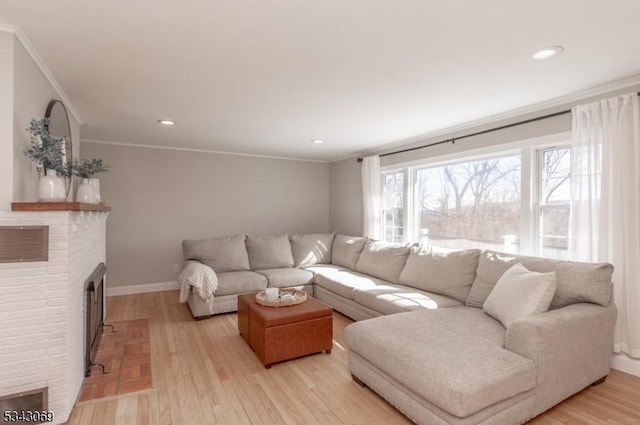 living room featuring crown molding, a brick fireplace, light wood-style floors, and baseboards