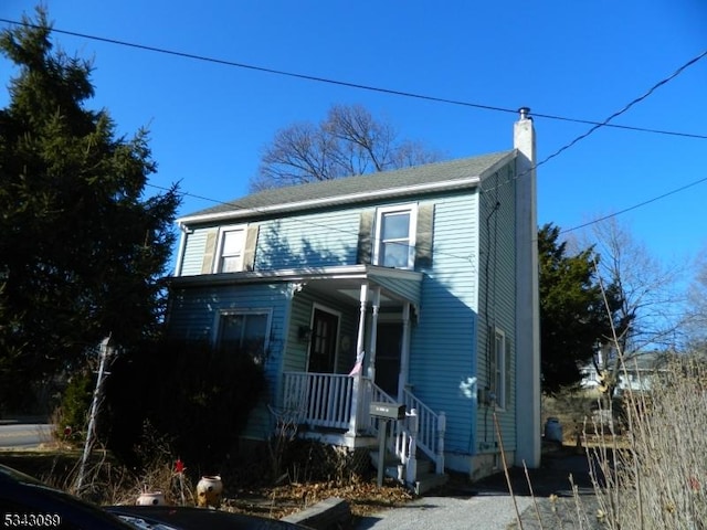 traditional-style house featuring a porch and a chimney