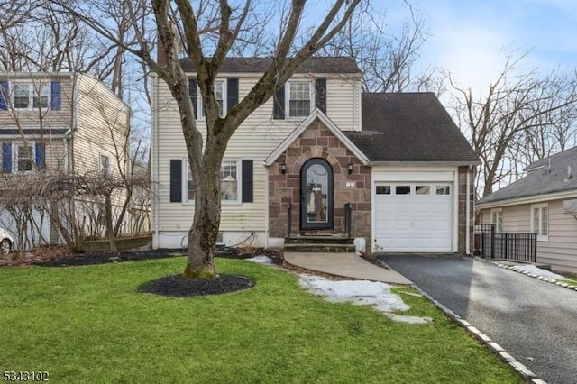 view of front of home featuring a front yard, an attached garage, stone siding, and driveway