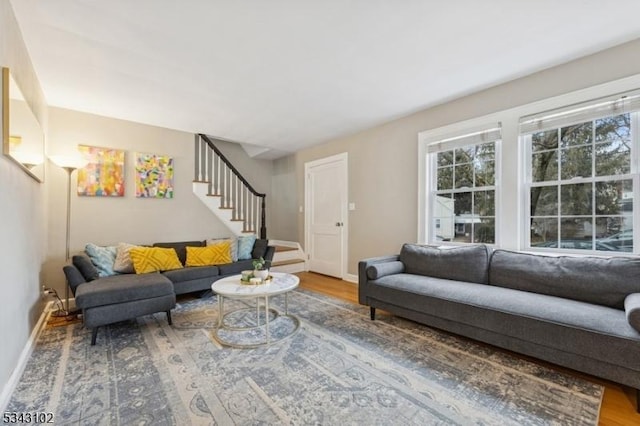 living room featuring stairs, baseboards, and wood finished floors