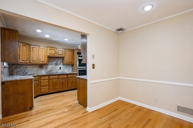 kitchen featuring crown molding, double oven, light wood-type flooring, decorative backsplash, and brown cabinetry