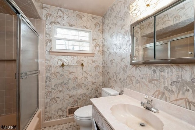 bathroom featuring vanity, visible vents, wallpapered walls, toilet, and combined bath / shower with glass door