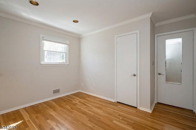 empty room with visible vents, baseboards, light wood-style floors, and ornamental molding