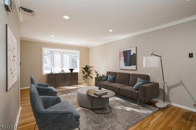 living area with visible vents, baseboards, wood finished floors, and crown molding