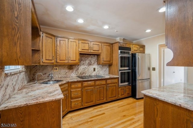 kitchen with a sink, light stone counters, appliances with stainless steel finishes, and brown cabinets