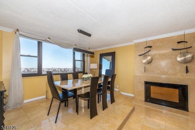 dining area featuring baseboards, a tile fireplace, and ornamental molding