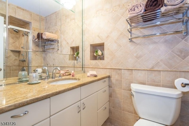 full bath with tiled shower, toilet, vanity, and tile walls