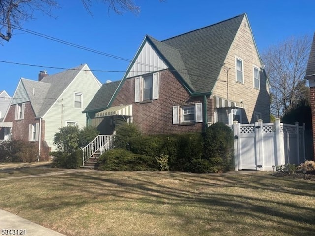 view of front of property with brick siding, a gate, a front lawn, and fence